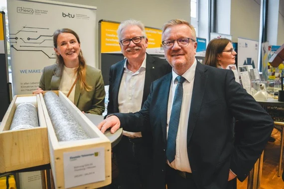 Eine Frau und drei Männer lächeln in die Kamera