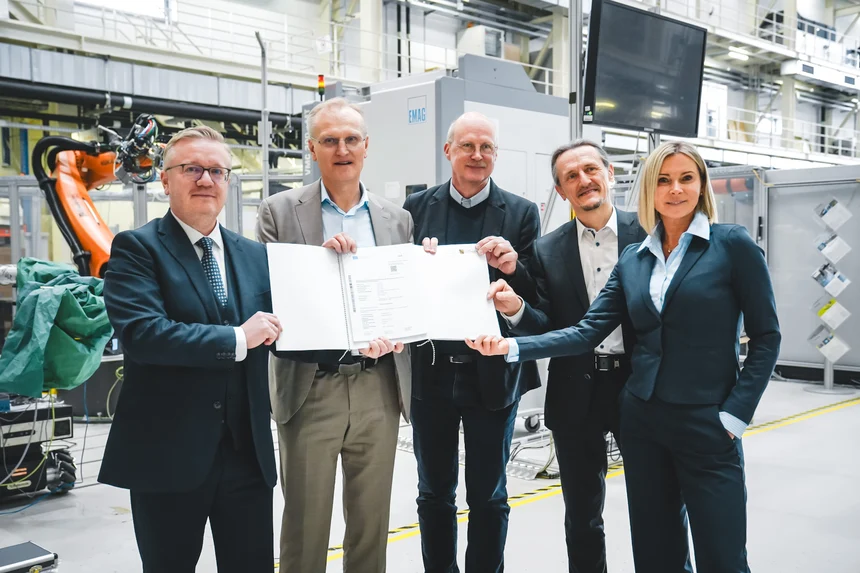 Fünf Personen mit zwei Fördermittelbescheiden in einer Industriehalle