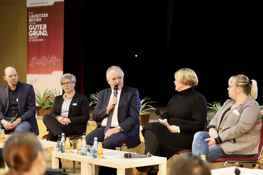 Zu sehen ist Staatsminister Schmidt im Podium mit seinen Gästen